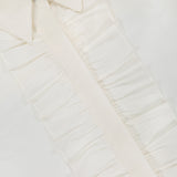 Close-up of the TWP Next Ex Ruffle Blouse in ivory white, featuring ruffled detailing along the button placket. Made from smooth, lightweight fabric, this medium-sized blouse blends comfort and sophistication—perfect for women's workwear.