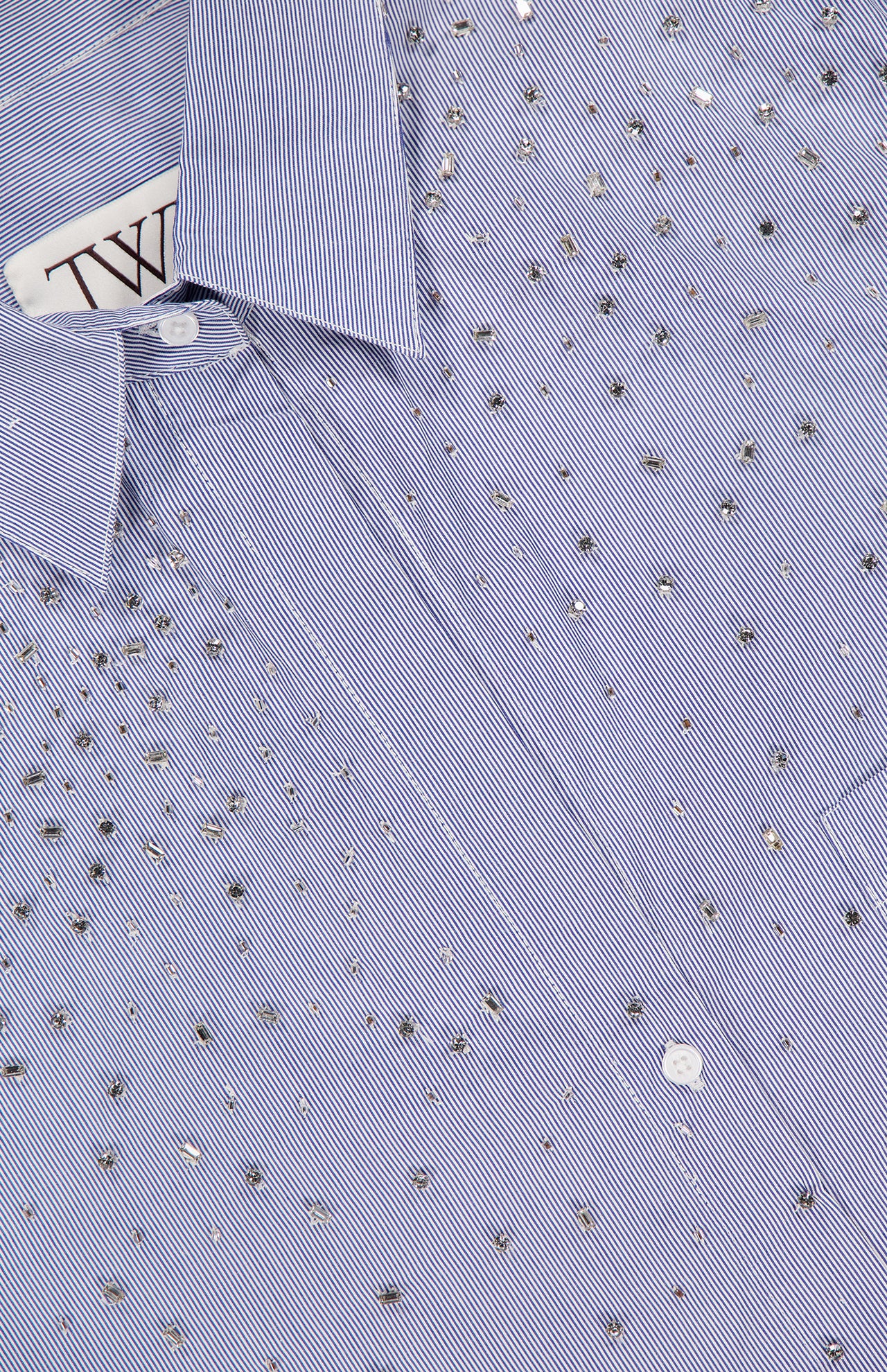 A close-up of the TWP Next Morning Shirt with Crystals, an oversized blue and white striped Italian cotton button-down featuring scattered silver studs, showing part of the collar and a visible label.
