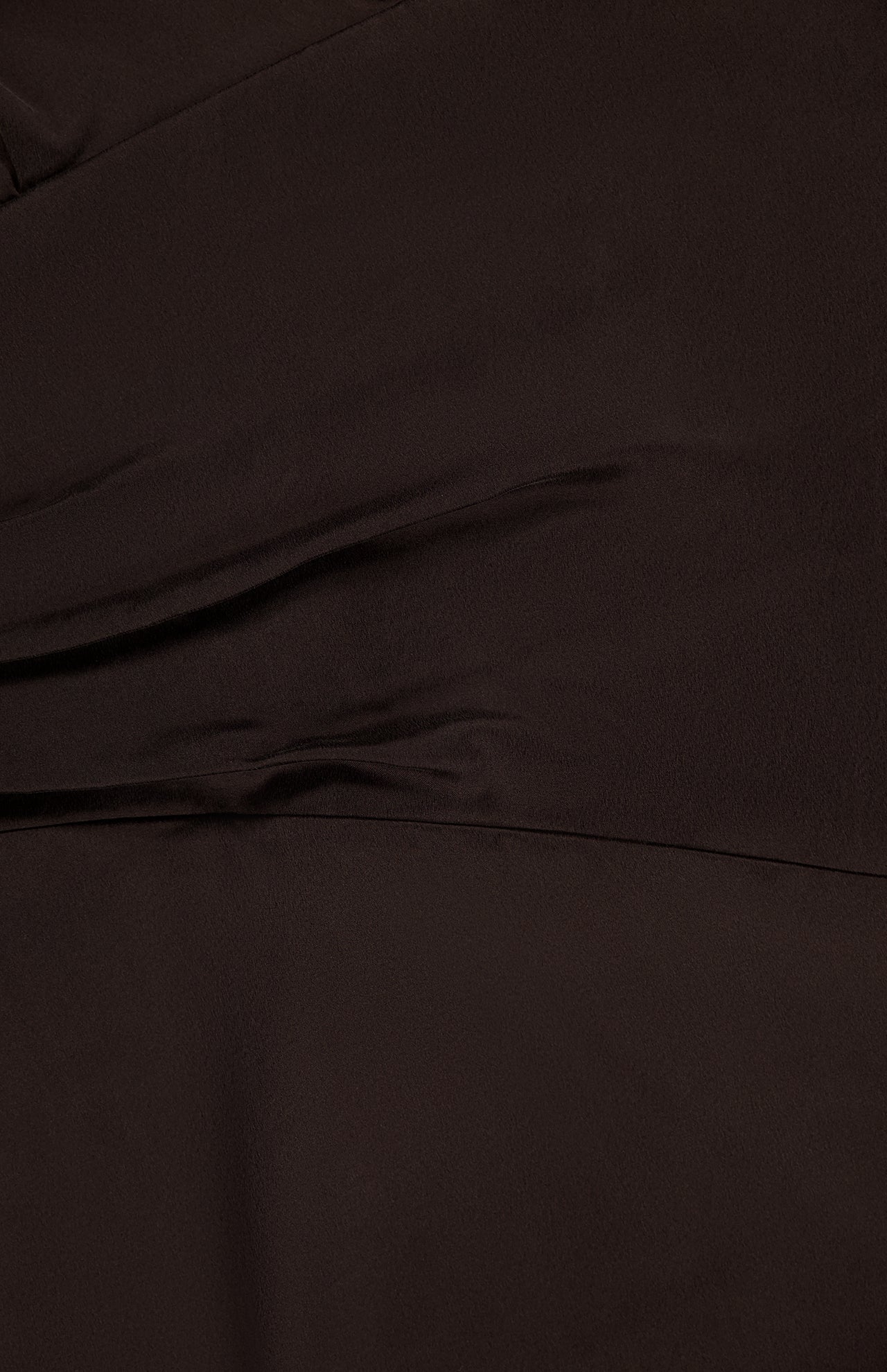 Close-up of the TWP On the Side Stretch Silk Dress in dark brown, highlighting its soft folds, subtle texture, and gentle diagonal creases for a look reminiscent of a ruched maxi dress with a smooth finish.