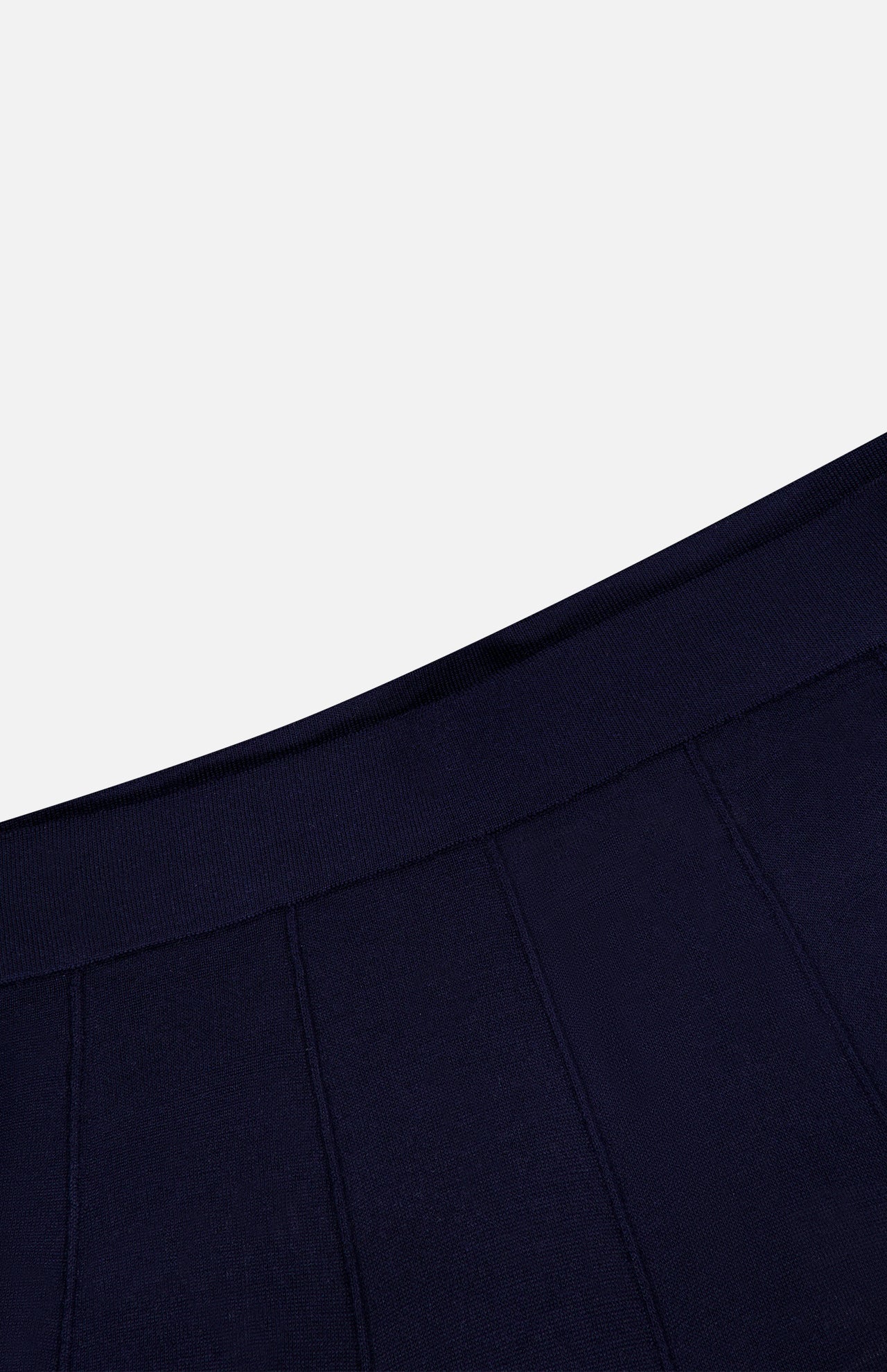 Close-up of a navy blue fabric with vertical seam lines and a ribbed waistband, set against a plain white background—perfect for highlighting the refined details of the TWP Seamed Maxi Skirt.