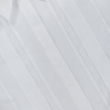 Close-up of the TWP Short Lived Placket with Cherry Pleats Shirt, a cropped white dress shirt featuring vertical pleats and a pointed collar. Neatly pressed and laid flat with the top button undone, this piece showcases a modern update on classic women’s workwear. Part of the inside label is visible, emphasizing its refined design.