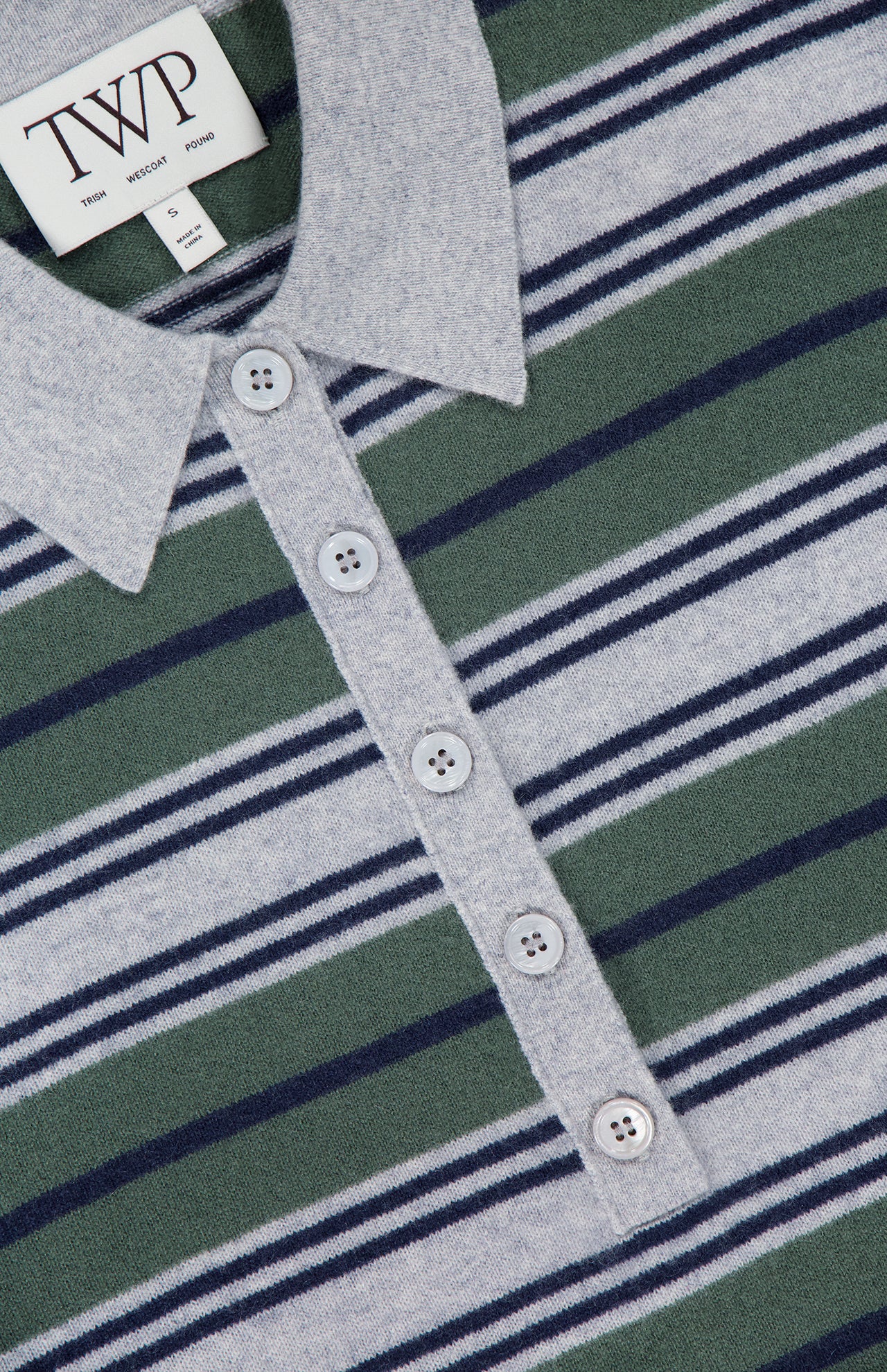 Close-up of the TWP Short Sleeve Polo with Stripes, designed as modern women's workwear. The shirt showcases gray, green, and navy horizontal stripes and features a button placket. Inside the collar is a white TWP label with smaller text beneath.