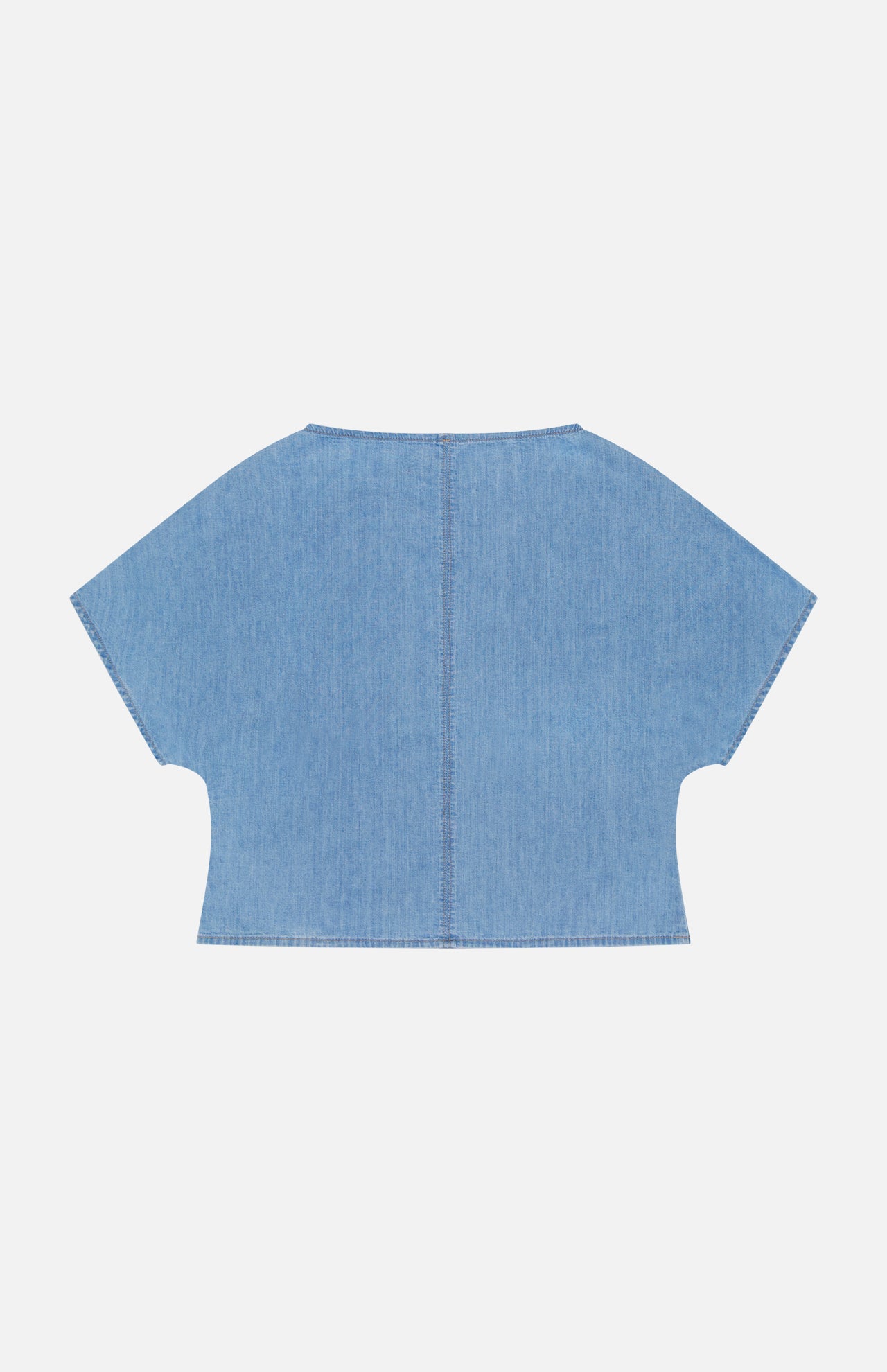 The Simple T Top by TWP is a lightweight, light blue denim shirt with wide sleeves and a relaxed, boxy cropped fit. Visible center and edge stitching add detail—ideal for effortless women’s workwear. Shown flat on a white background.