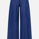 Back view of TWP’s Song Sung Blue Jean in Dark Stone, featuring wide-leg blue denim crafted from a cotton linen blend, with two rear pockets, a high waist, and a loose fit, displayed against a plain white background.
