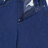 Close-up of the Song Sung Blue Jean in Dark Stone by TWP, featuring relaxed blue denim with a partially open zipper and button fly that reveals the inner pocket lining and a TWP label on the waistband.