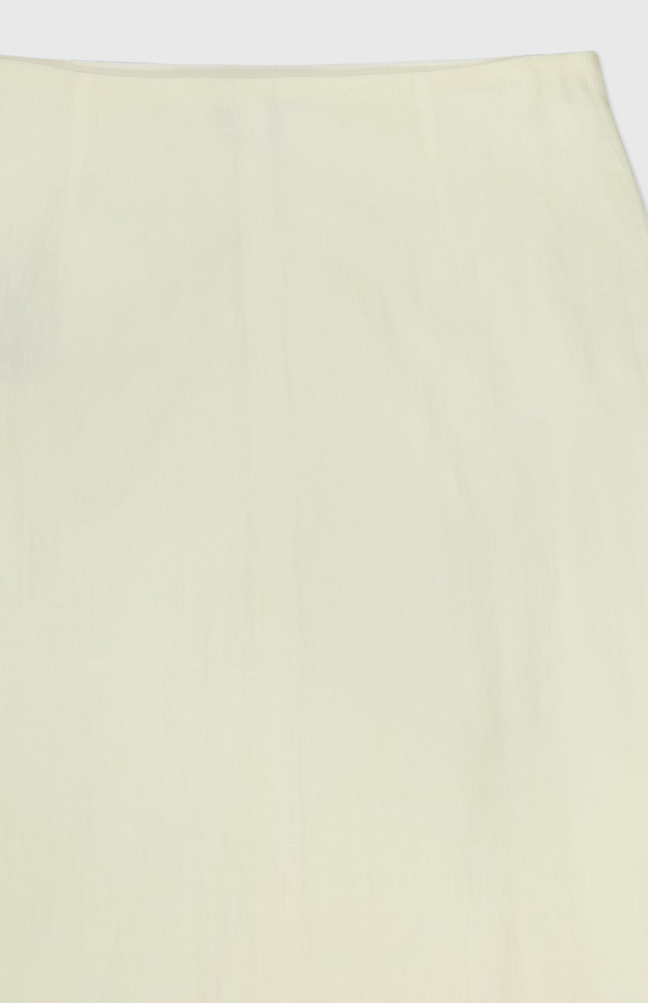 A close-up of the TWP A-Line Linen Skirt displays its light yellow, smooth linen fabric with subtle creases and no visible patterns.