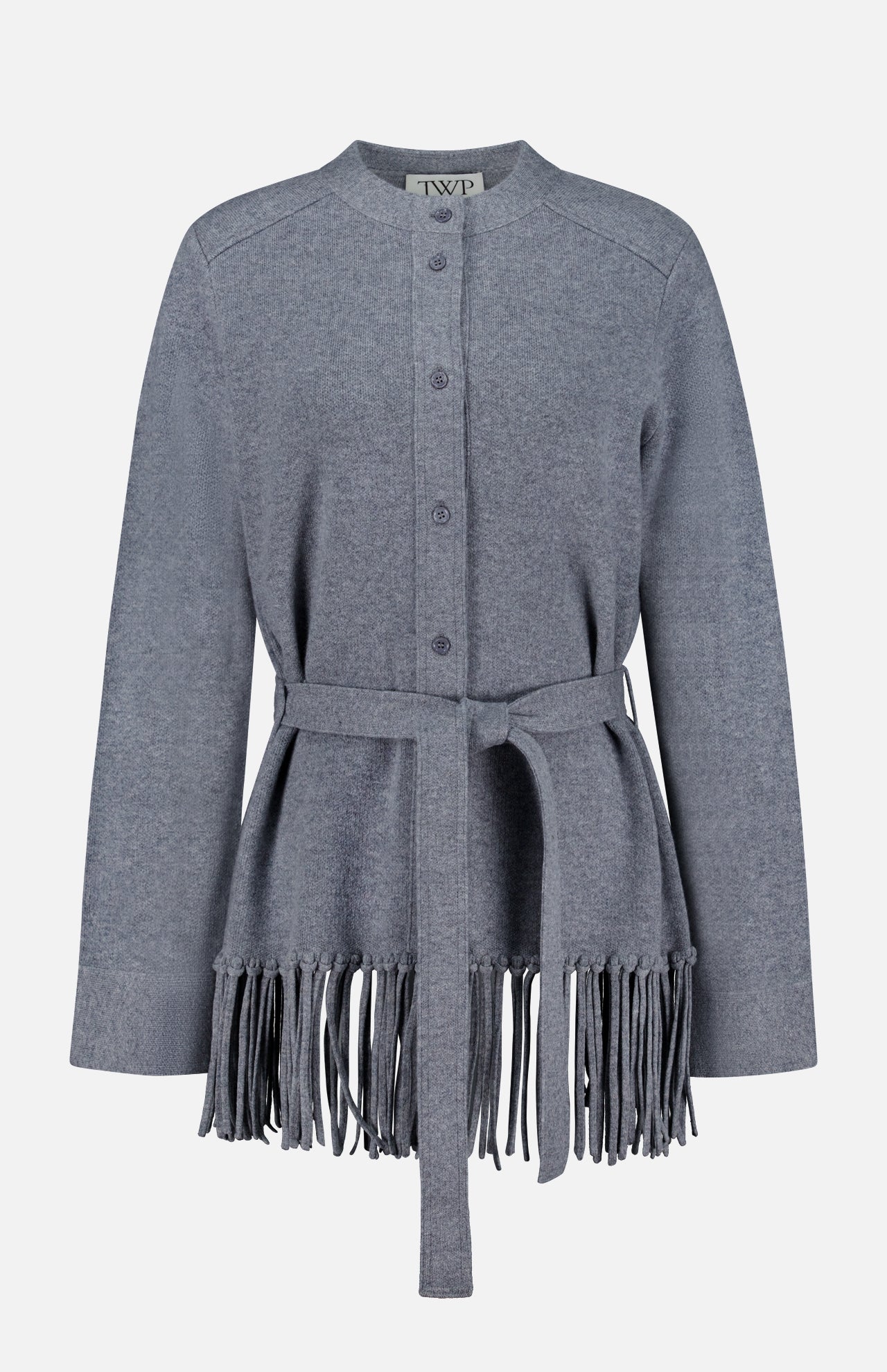 The TWP Thea Fringed Hem Cardigan is a gray button-up style, expertly crafted from luxurious Italian cashmere, featuring a belted waist and long fringe detailing at the hem—an elevated staple for women’s workwear, shown against a white background.