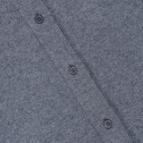 Close-up of a heather gray Thea Fringed Hem Cardigan from TWP, featuring four dark buttons and a visible TWP brand label at the collar. The fabric has a soft, textured appearance reminiscent of Italian cashmere, making it an elegant addition to women’s workwear.