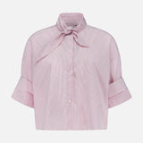 The TWP Tie One On Striped Shirt features red and white vertical stripes, short sleeves with wide cuffs, a bow tie collar, and front buttons—ideal for nautical looks or chic women’s workwear.