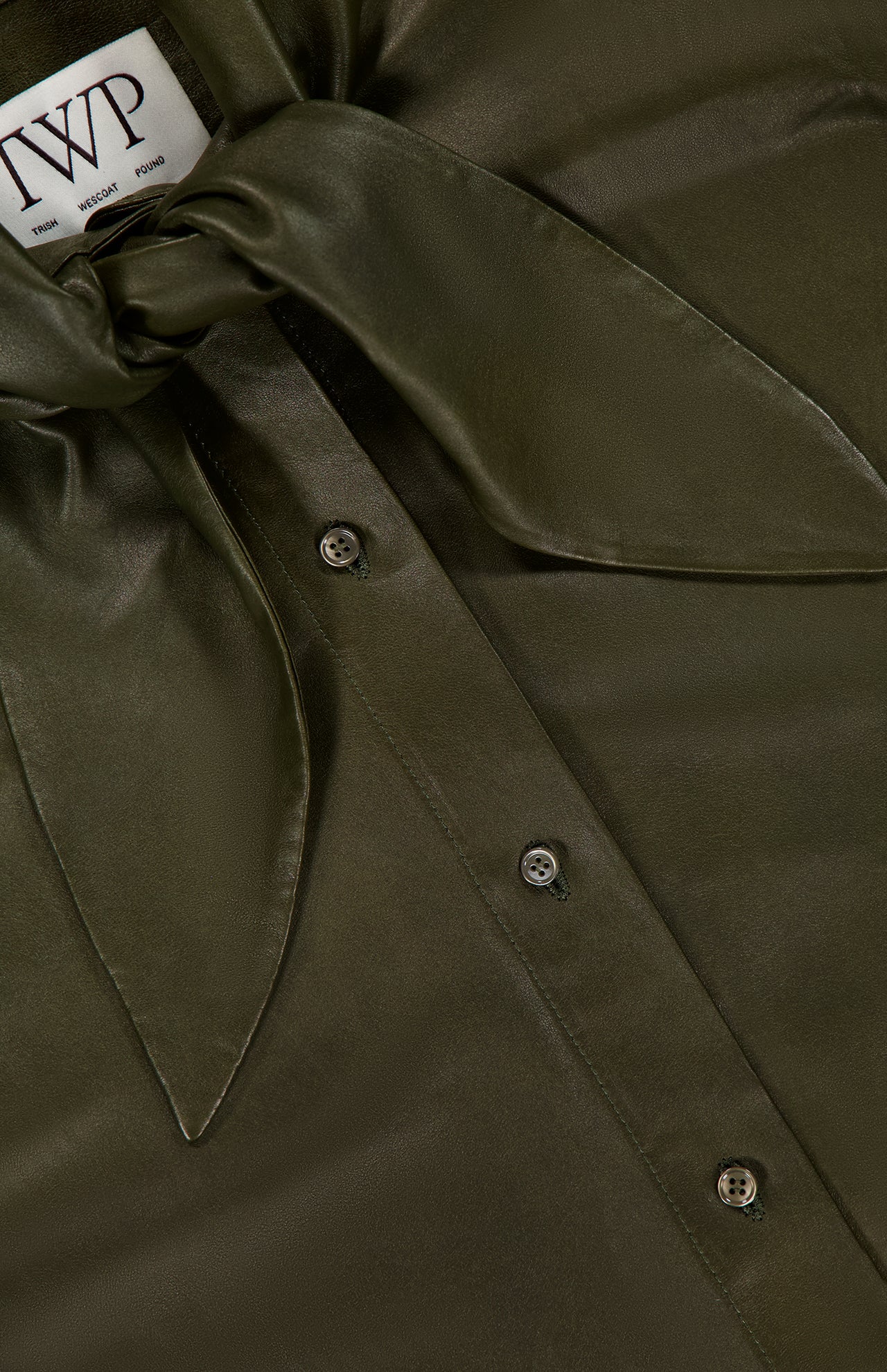 Close-up of the Tied Up In You Shirt by TWP in olive green satin, featuring an oversized neck tie and front button closure. The TWP brand label is visible at the neckline.
