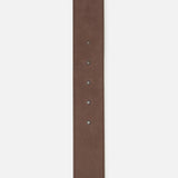 A close-up of the TWP Wide Leather Belt for women in brown leather, featuring five holes and visible edge stitching, is displayed vertically against a white background. The pointed tip and luxury craftsmanship highlight its workwear appeal.