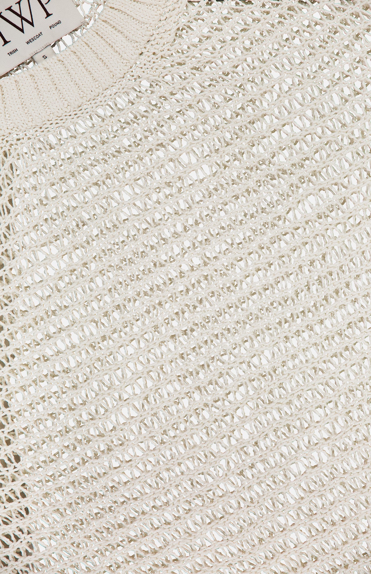 Close-up of TWP's cream-colored Wide Crewneck Long Sleeve Pullover Sweater, featuring an intricate open-knit textured weave. The neckline and part of the inner tag appear at the top—ideal as stylish women's workwear.