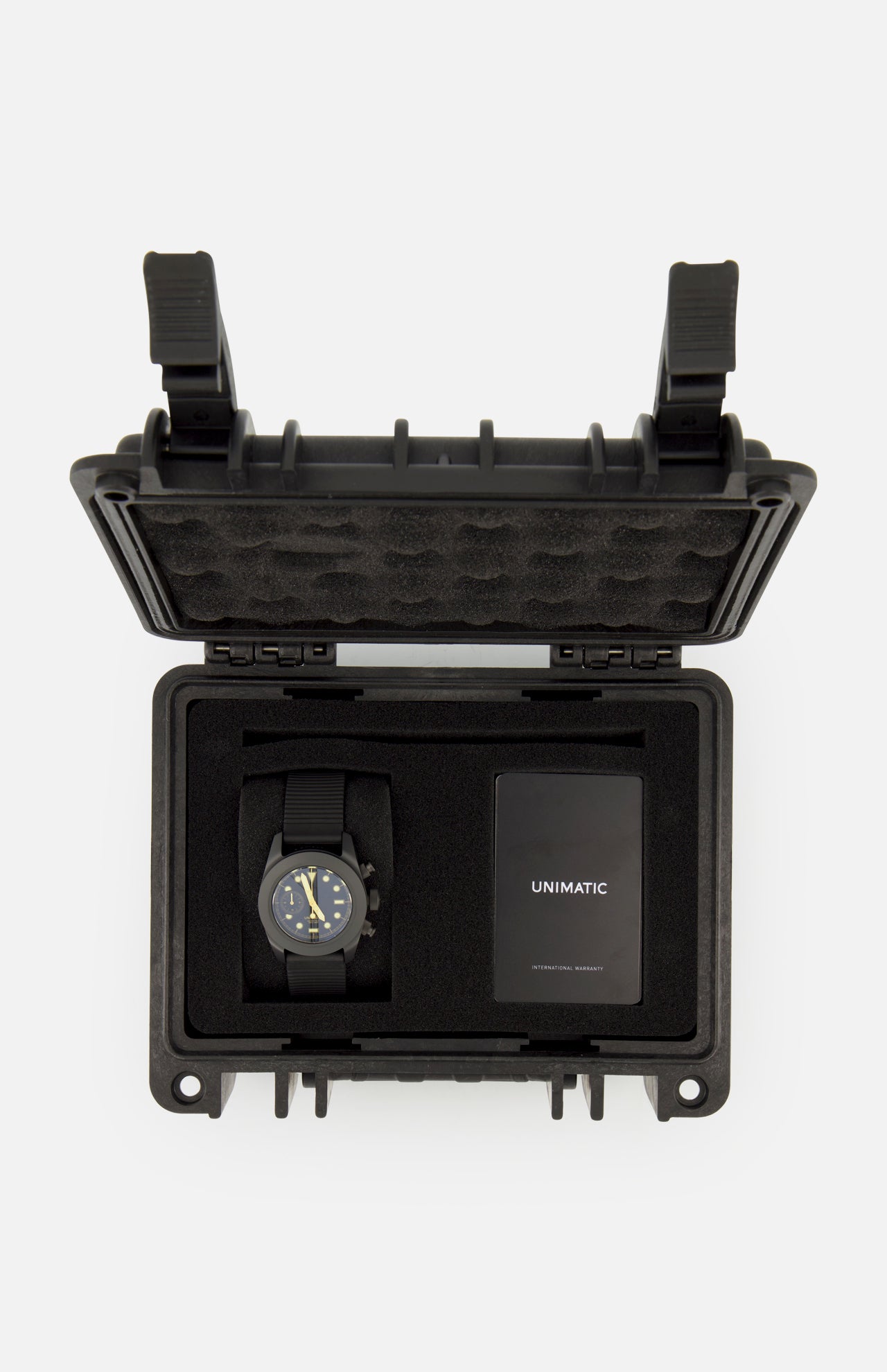 A UNIMATIC Watch Kit U3FB-ROPS, featuring a black Italian diving watch and an instruction manual, is neatly arranged inside an open black protective foam case.