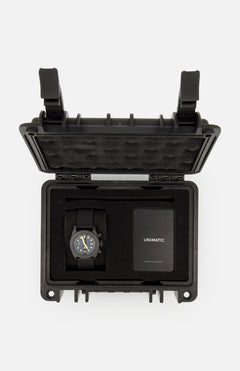A UNIMATIC Watch Kit U3FB-ROPS, featuring a black Italian diving watch and an instruction manual, is neatly arranged inside an open black protective foam case.