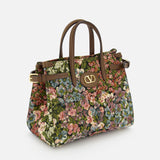 The Antibes Small Floral Tote Bag by VALENTINO GARAVANI features jacquard fabric, brown leather handles and trim, vintage floral design, and signature gold VLogo hardware on the front.