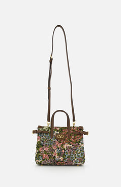 The VALENTINO GARAVANI Antibes Small Floral Tote Bag is a jacquard handbag with two handles, a long adjustable shoulder strap, a colorful floral pattern, and gold VLogo hardware on the front.