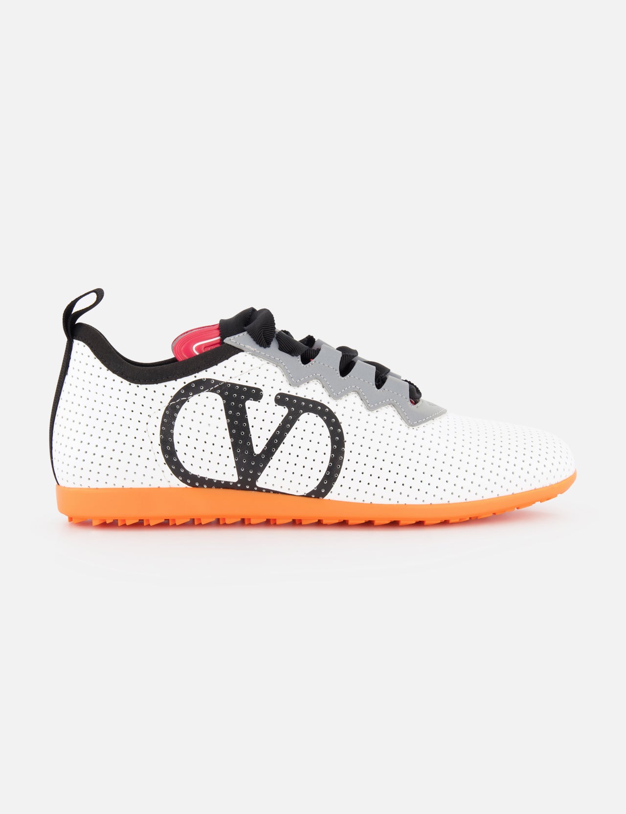VALENTINO GARAVANI Chromathon Orange Sole Logo Sneaker: White leather, black laces, large black V logo on the side, orange sole, perforated low-top soccer-inspired design. Photographed on a plain white background.