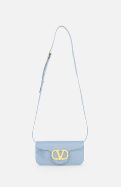 A light blue VALENTINO GARAVANI Loco Swarovski Crystal Clutch with an adjustable strap and a prominent gold VLogo Signature clasp on the front flap, displayed against a plain white background.