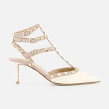 The Rockstud Ankle Strap Heel T.65 by VALENTINO GARAVANI is a beige patent leather pump with three nude ankle straps, gold rockstud accents, and a pointed toe, photographed against a plain white background.