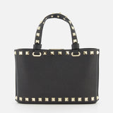 The VALENTINO GARAVANI Rockstud Removable Chain Strap Mini Bag is a black leather purse with two handles, featuring rows of gold pyramid studs along the edges and handles, displayed against a plain white background.