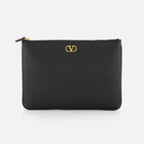The VALENTINO GARAVANI V Logo Signature Medium Flat Pouch is a black leather clutch featuring a gold logo on the front, shown against a white background.