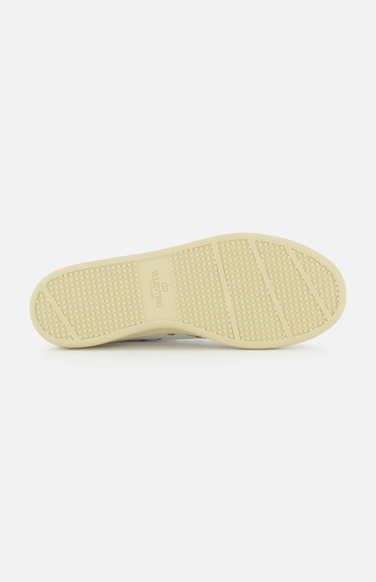 The image displays the beige rubber sole of the Valentino Garavani Royco Sneaker, featuring textured grip patterns and VALENTINO GARAVANI branding at the center, photographed against a white background.