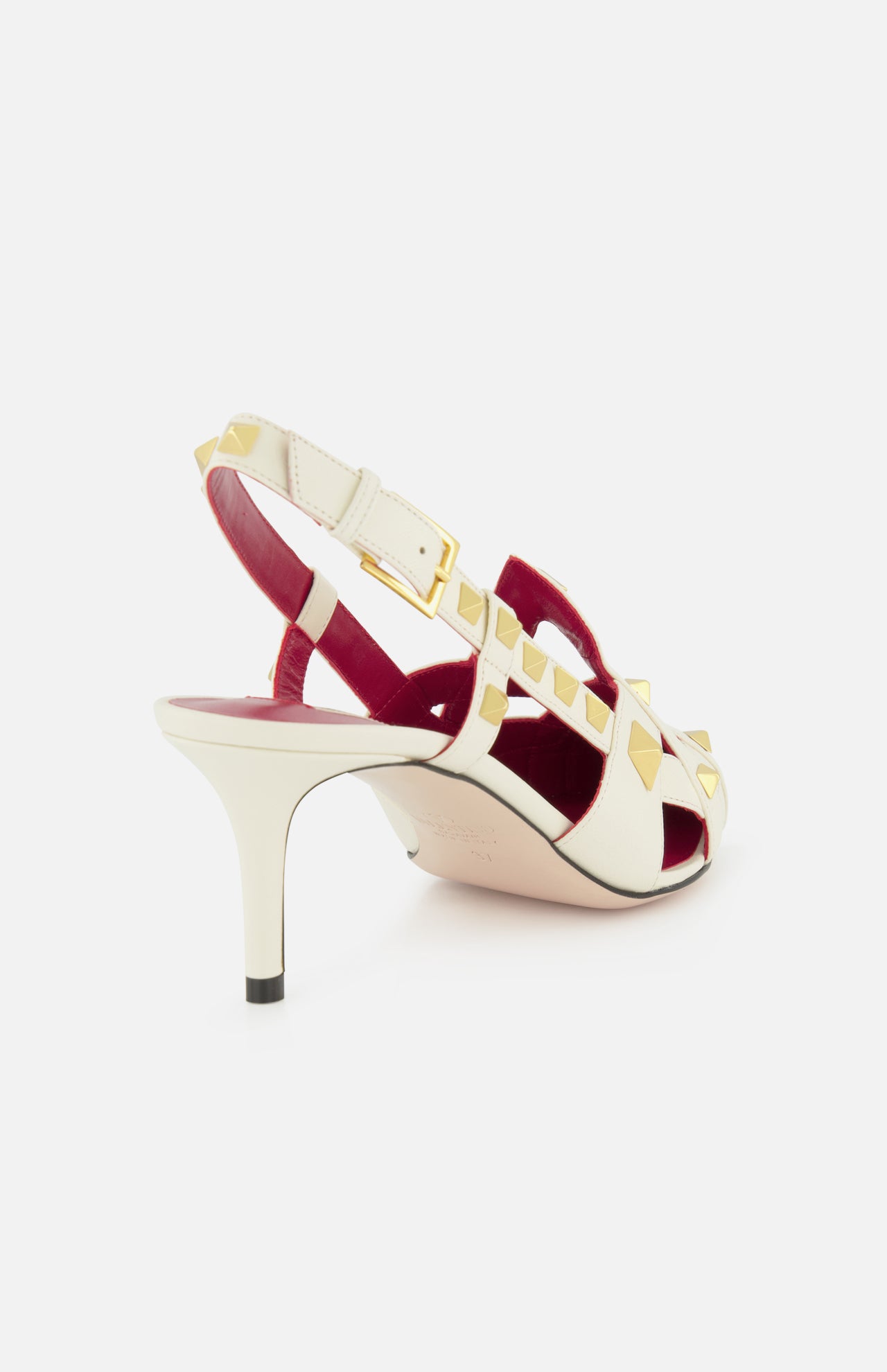 The Valentino Garavani Studdy Sling Back Heel T.65 features ivory leather, gold pyramid studs, a slim buckle ankle strap, red lining, an open toe, and a chic mid-height tapered heel for added elegance.