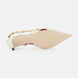 The VALENTINO GARAVANI Studdy Sling Back Heel T.65 features a white pointed toe, gold pyramid studs, pink trim, an elegant ankle strap, and smooth sole—showcasing the brand’s signature design details.