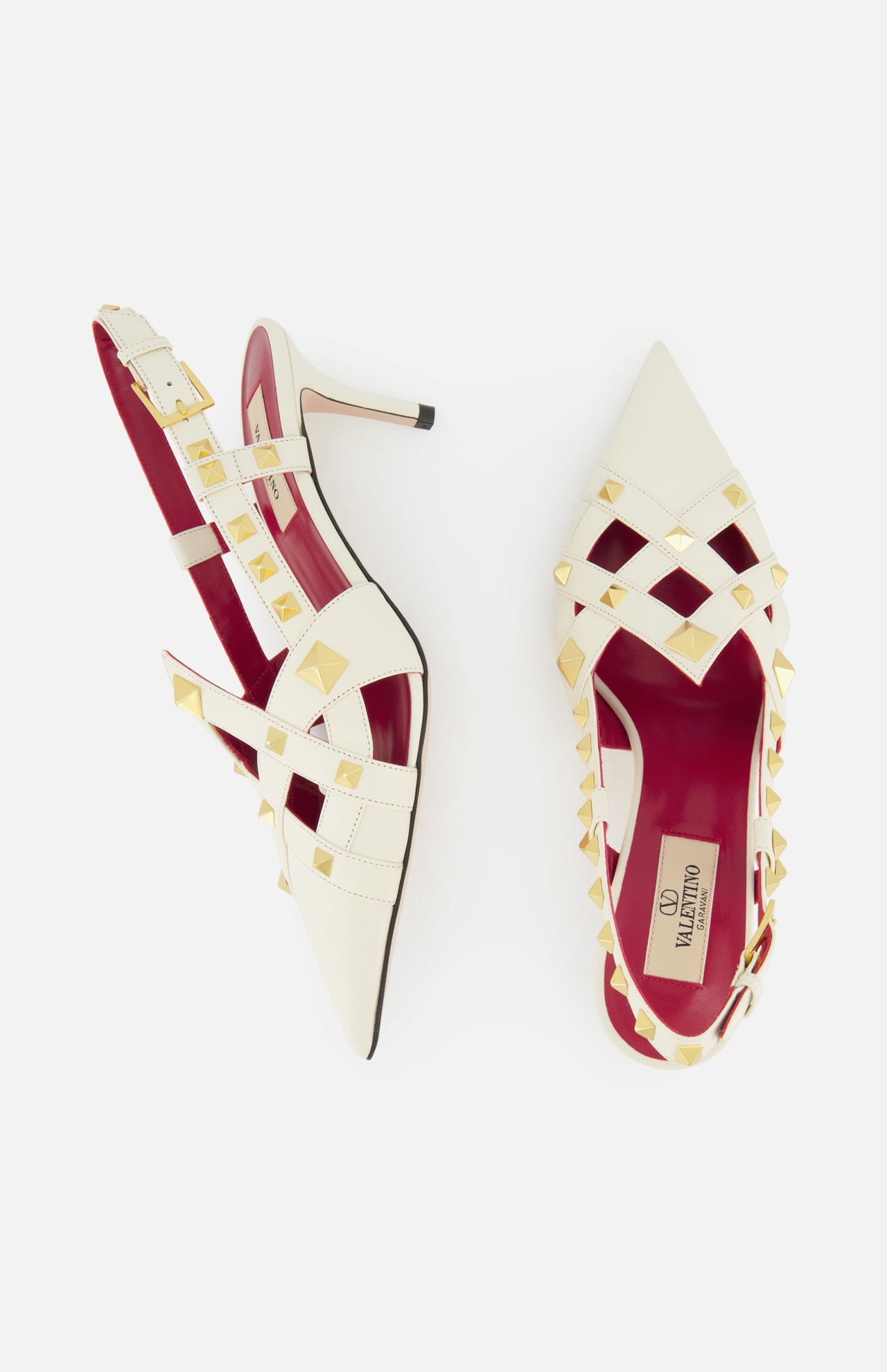 VALENTINO GARAVANI’s Studdy Sling Back Heel T.65 features ivory leather, pointed toes, gold pyramid studs, crisscross ankle straps, red insoles, and slender heels—displayed on a white background.