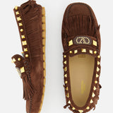 The image shows the VALENTINO GARAVANI VG Plaster Caster Driver Loafer T.05: brown suede bohemian loafers with gold pyramid studs, fringe trim, tassels, and a rubber sole—one viewed from above, one from the side on a white background.
