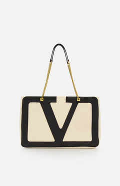 The VALENTINO GARAVANI Viva Superstar Large Tote Bag showcases beige leather with bold black V-shaped trim and gold chain handles on black straps, making this chic accessory stand out against a plain white background.