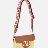 The VALENTINO GARAVANI Alltime Cherry Strap Shoulder Bag features a woven straw base, brown leather flap with gold V logo, and a wide red strap embroidered with cherry motifs for a floral accent on this chic crossbody clutch.