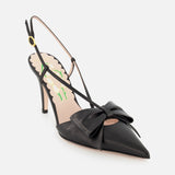 The VALENTINO GARAVANI Bowow Sling Back Heel is a black leather pump with a pointed toe, front bow detail, adjustable ankle strap, and floral-patterned insole, shown on a white background.