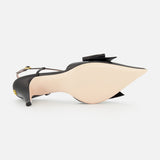 The VALENTINO GARAVANI Bowow Sling Back Heel, a black leather pointed-toe pump with an adjustable ankle strap and decorative bow, is shown on its side, highlighting its smooth, light-colored sole.