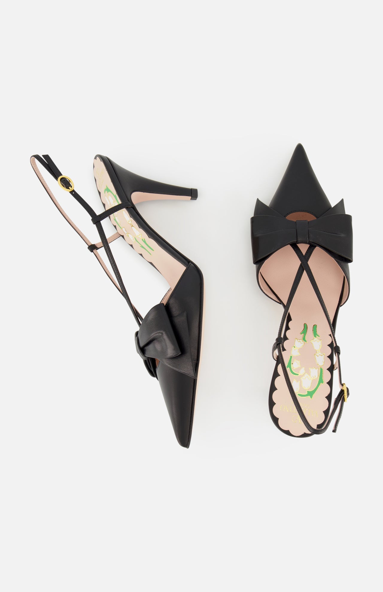 The VALENTINO GARAVANI Bowow Sling Back Heel is a pair of black leather pointed-toe pumps with large front bows, adjustable ankle straps, floral-patterned insoles, shown against a white background.