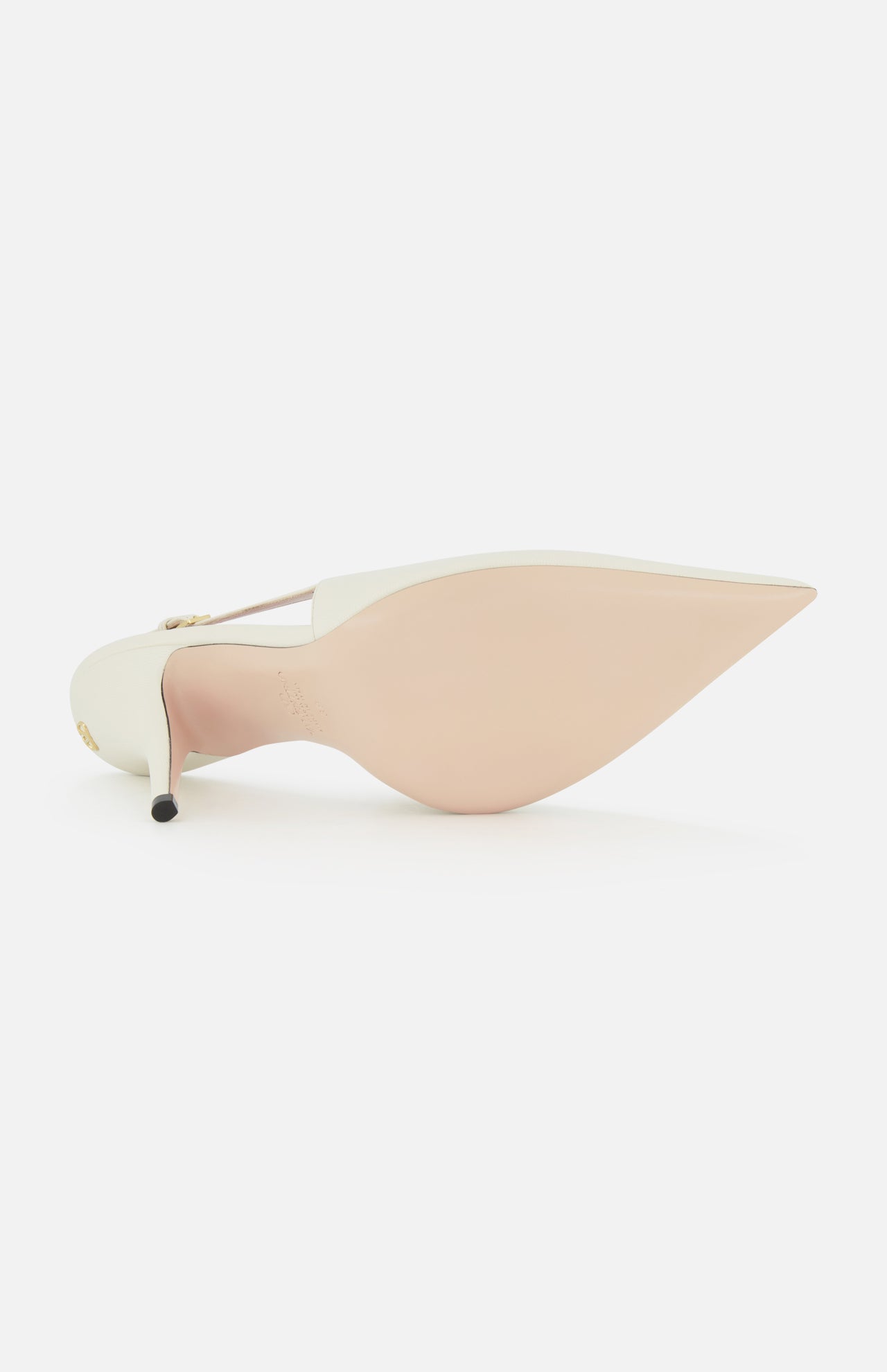 The Cuttie Sling Back Heel by VALENTINO GARAVANI is shown from the bottom, displaying its pointed toe, pale beige sole, white upper, and thin stiletto heel, with the ivory leather slingback positioned toe-up on a white background.