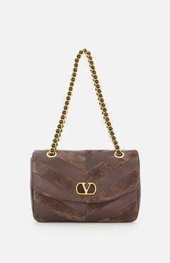 The Djuna Medium Chevron Shoulder Bag by VALENTINO GARAVANI is a brown designer leather shoulder bag with gold chain strap and gold logo clasp, featuring diagonal suede and leather panels, shown against a white background.