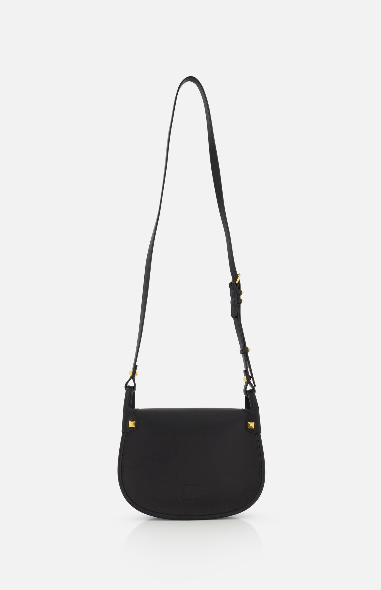 The VALENTINO GARAVANI Flaneuse Small Shoulder Bag is crafted from black leather with a long adjustable strap and gold-tone hardware. Its curved bottom and flap closure are shown elegantly against a plain white background.