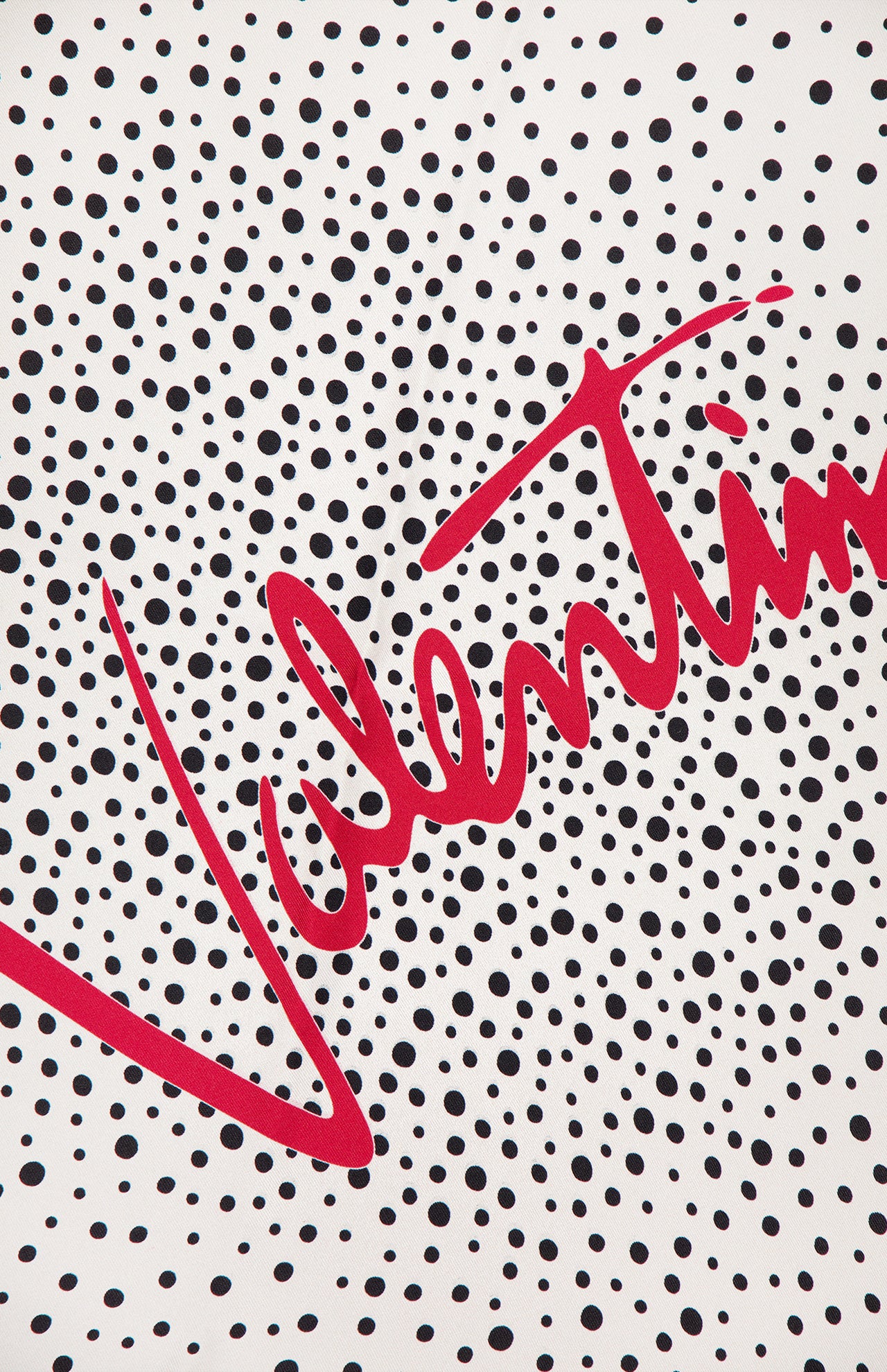 A white background with black polka dots and "VALENTINO GARAVANI" diagonally in bold red creates a striking Foulards Polka Dot Shawl—an elegant silk accessory made in Italy.