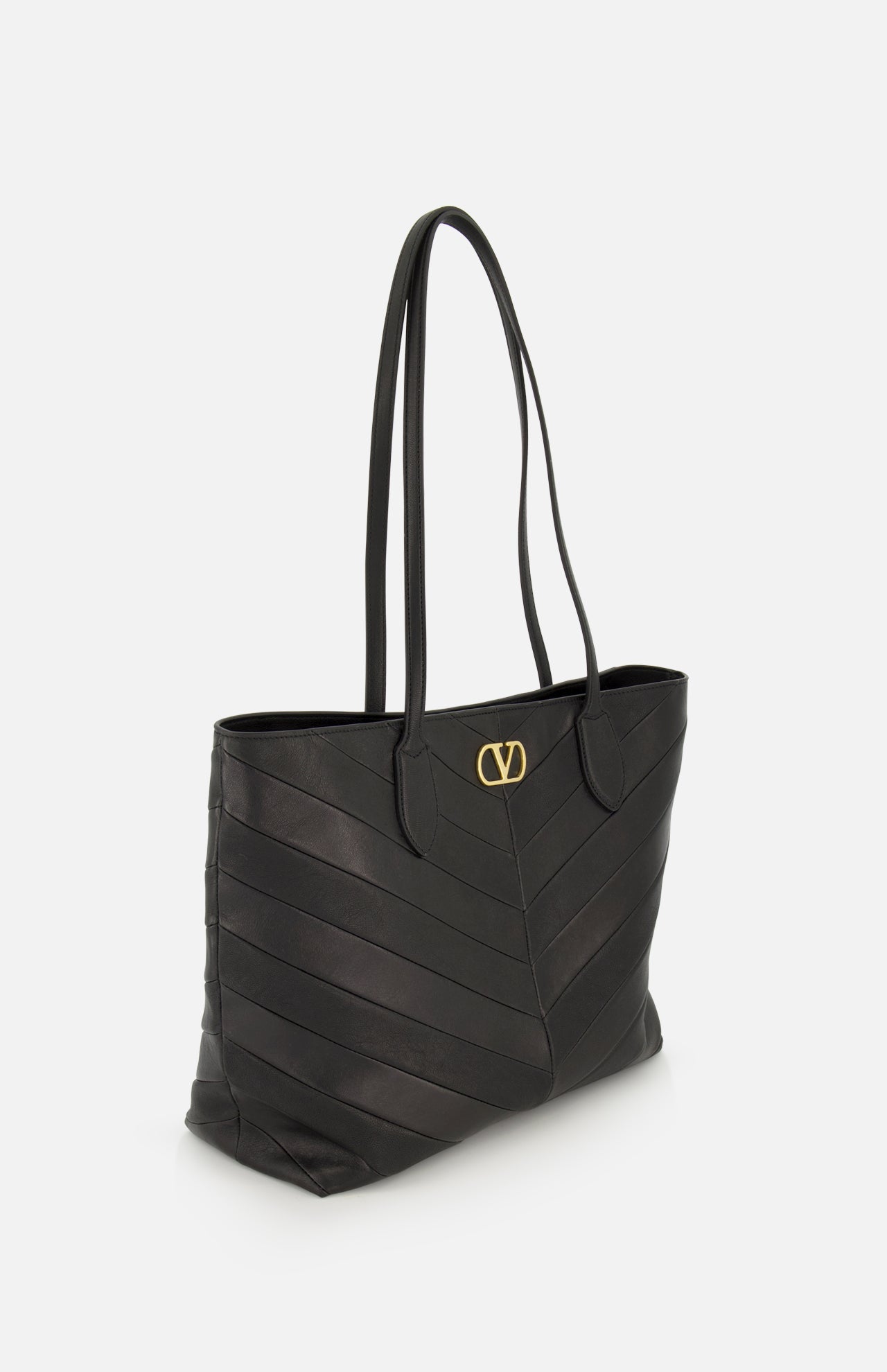 Valentino Garavani Jean Medium Tote Bag in black with chevron-stitched panels and a gold metal logo emblem on the front.