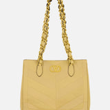The VALENTINO GARAVANI Laseine Small Tote Bag in yellow features a quilted chevron pattern, gold chain handles, and a gold front emblem, displayed against a plain white background.