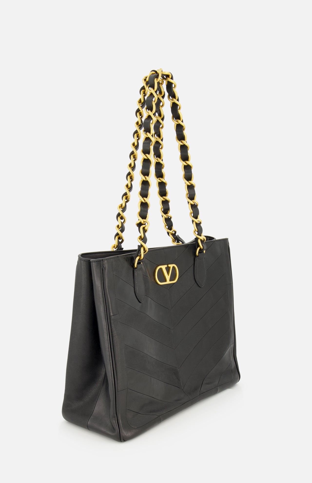 The Laseine Chevron Tote Bag by VALENTINO GARAVANI features a black leather chevron patchwork design, gold-tone double chain shoulder straps interwoven with black leather, and a signature gold V logo emblem on the front, displayed against a plain white background.