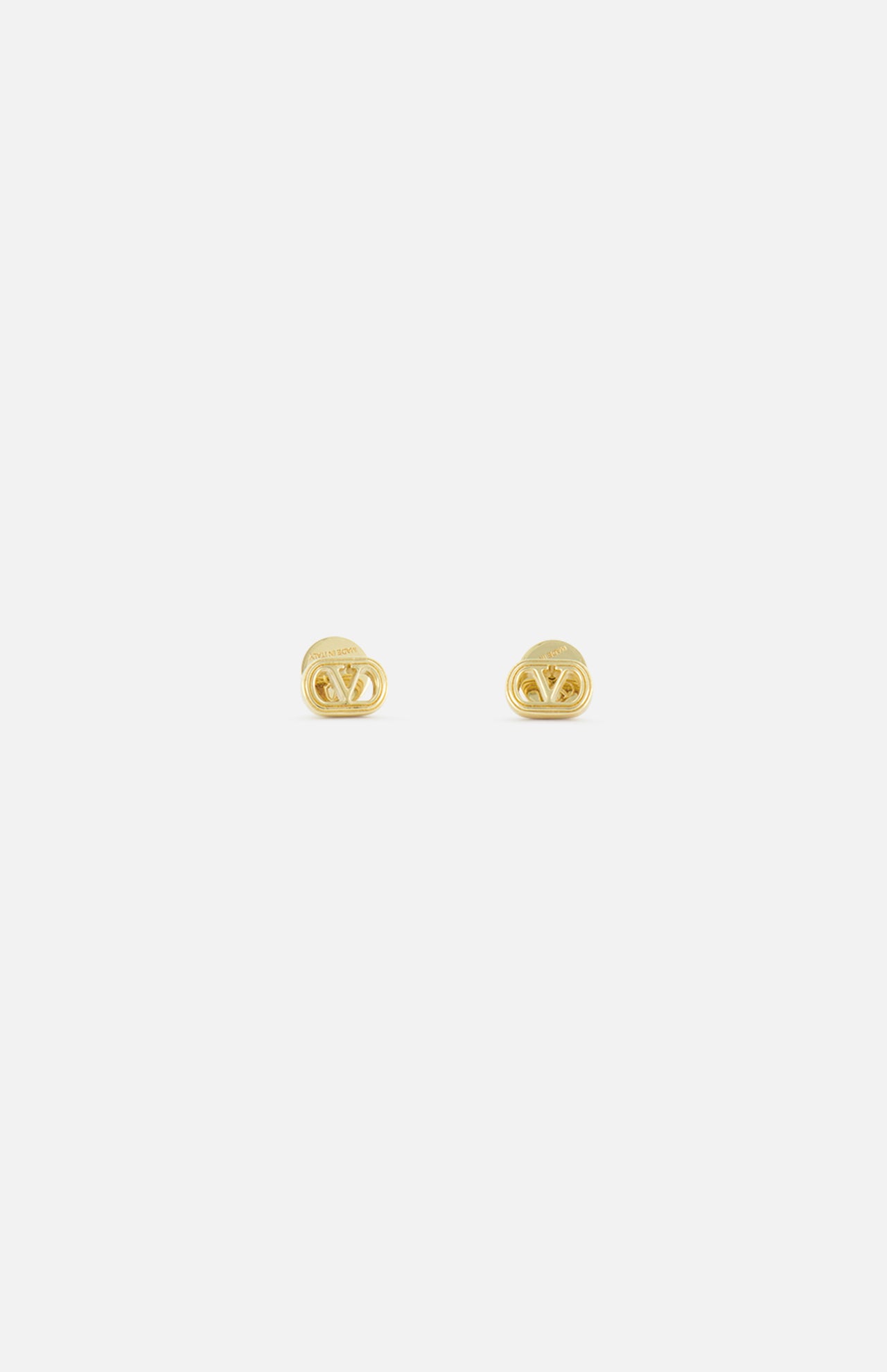 The VALENTINO GARAVANI Ovalette Logo Earrings are small, gold-tone earrings with an interlocking V design, crafted in Italy, shown on a plain white background.