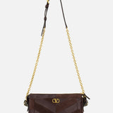 Introducing the Panthea Small Patchwork Shoulder Bag by VALENTINO GARAVANI—a luxurious handbag crafted from dark brown suede and leather. This sophisticated accessory is adorned with a gold chain strap, elegant gold hardware, and a signature small gold “V” emblem on the front. Subtle Swarovski crystal accents provide the perfect touch of sparkle to its refined design.