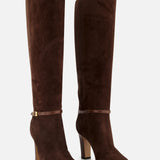The VALENTINO GARAVANI Pattie Suede Ankle Strap Boot is a pair of tall, dark brown suede boots featuring rounded toes, slim ankle straps, and a sleek block heel, displayed against a plain white background.