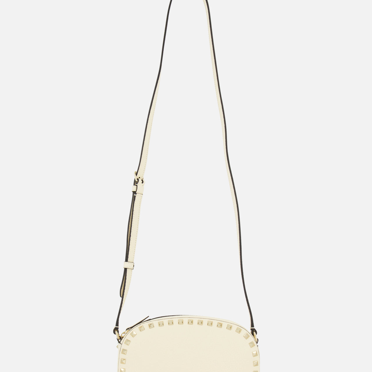The VALENTINO GARAVANI Rockstud Camera Case Bag is a cream oval handbag with gold-tone studs along the edges and an adjustable long strap, shown against a plain white background.