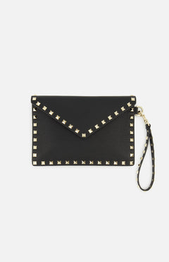 The Rockstud Medium Flat Pouch by VALENTINO GARAVANI is crafted from textured black leather in an envelope silhouette, accented with gold-tone square rockstuds outlining the edges and a matching studded wrist strap attached to one side. The pouch features a flap closure for secure storage.