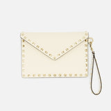 The VALENTINO GARAVANI Rockstud Medium Flat Pouch is an ivory clutch with a classic envelope design, embellished with gold rockstuds along the edges and featuring a detachable wrist strap, displayed against a plain white background.