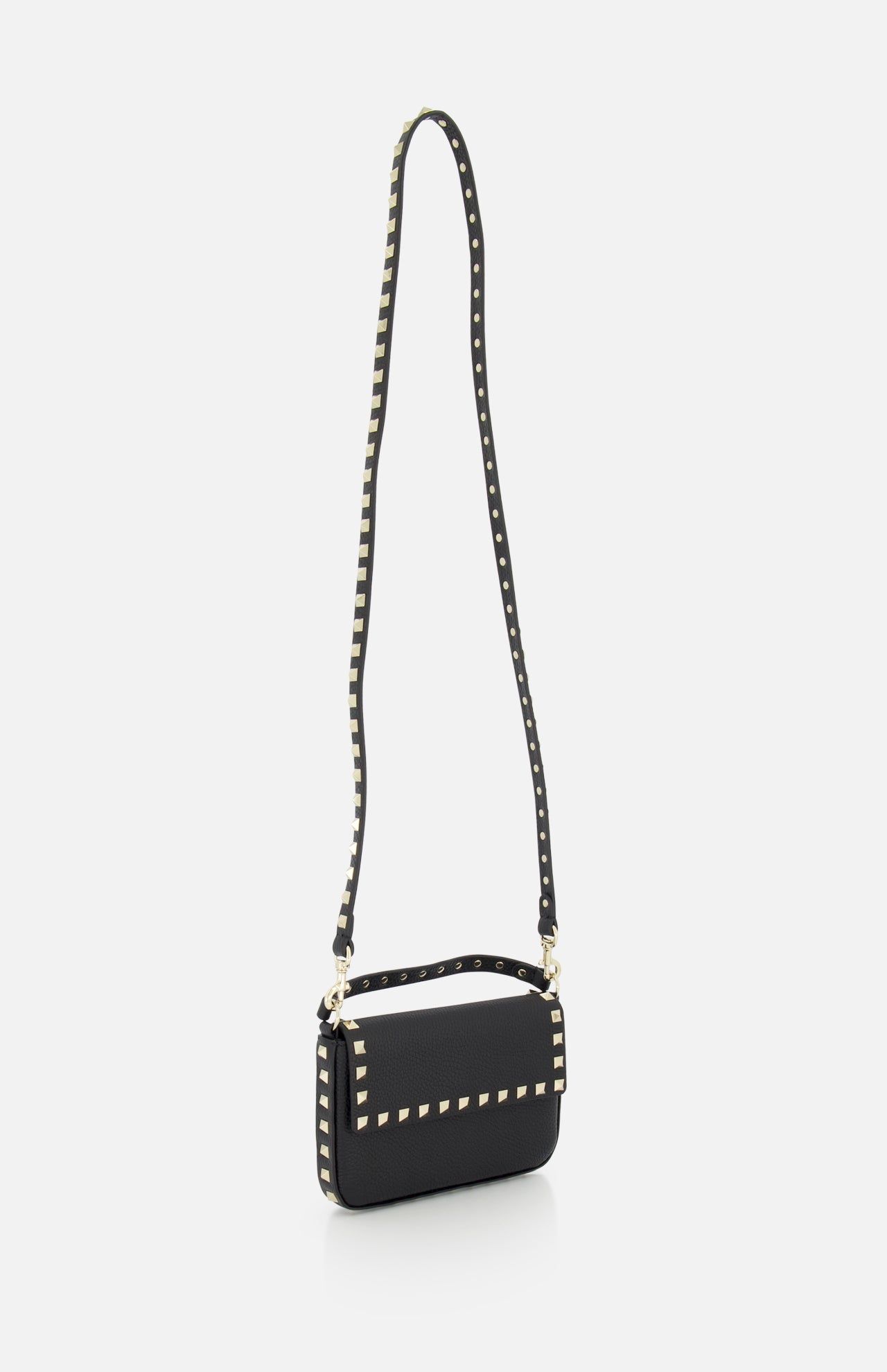 The VALENTINO GARAVANI Rockstud Leather Mini Bag is shown against a white background, featuring black grainy leather, a flap closure, long shoulder strap, and signature rockstud trim along the edges.