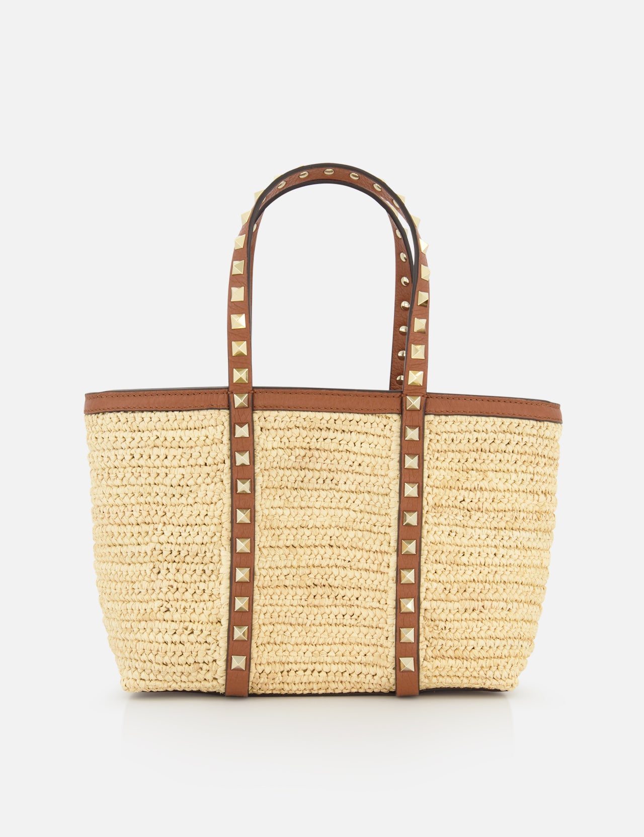 The VALENTINO GARAVANI Rockstud Mini Tote Bag is crafted from woven raffia and leather with brown handles, gold rockstud accents, and an open-top rectangular design for easy access.